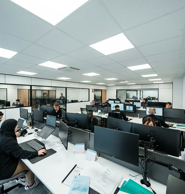 An operations floor: rows of desks with monitors and paperwork under even overhead light.